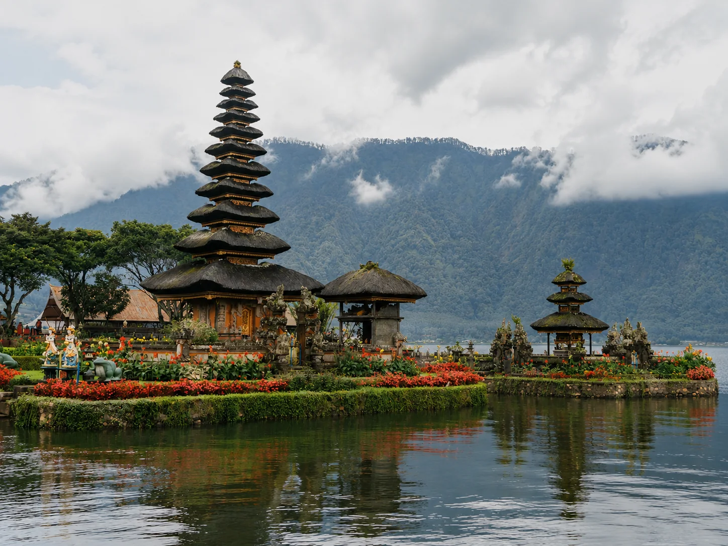 Balinese temple pavilions and community grounds beside a lake and mountain landscape